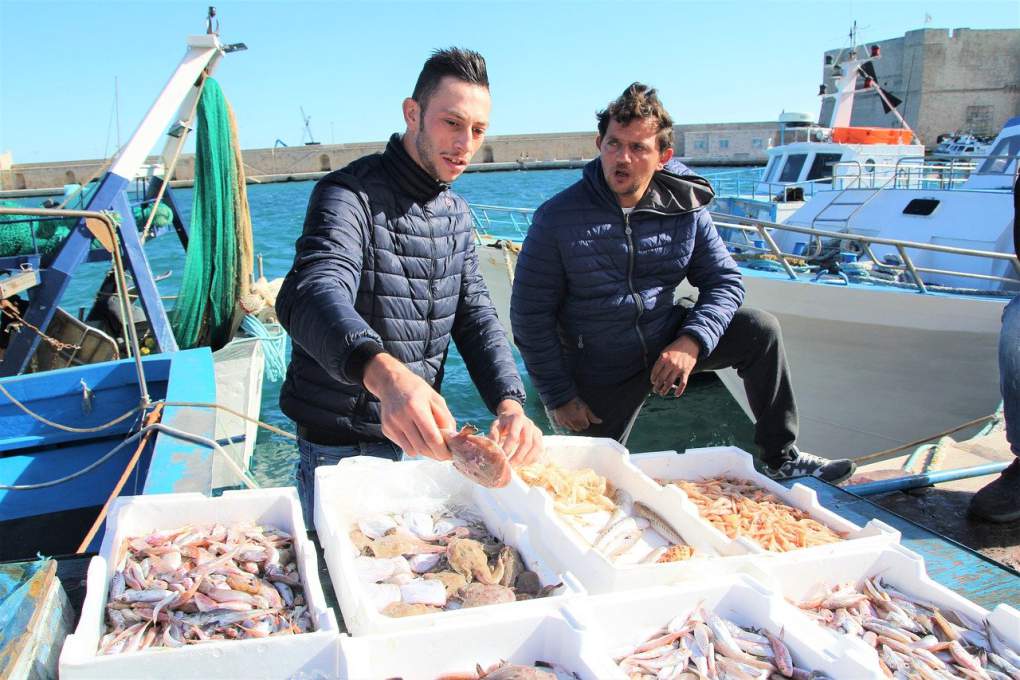 魚を持つイタリア人とそれを見る男性