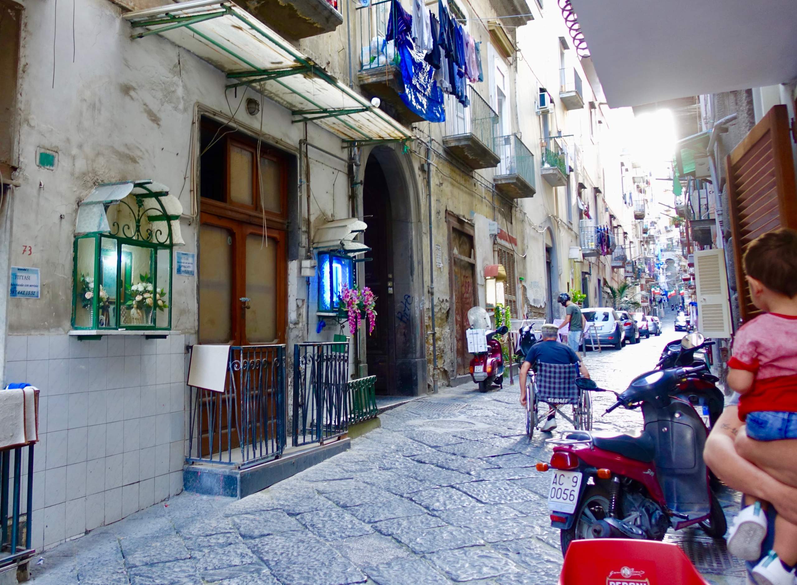 夕方になり、電気が灯る路地に設置された祠