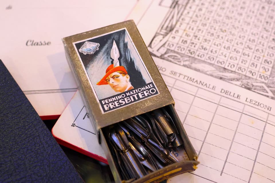 プレスビテロ社の万年筆の鋼製ペン先。後方に見えるのは、かつてイタリアの小学校で使われていたノート