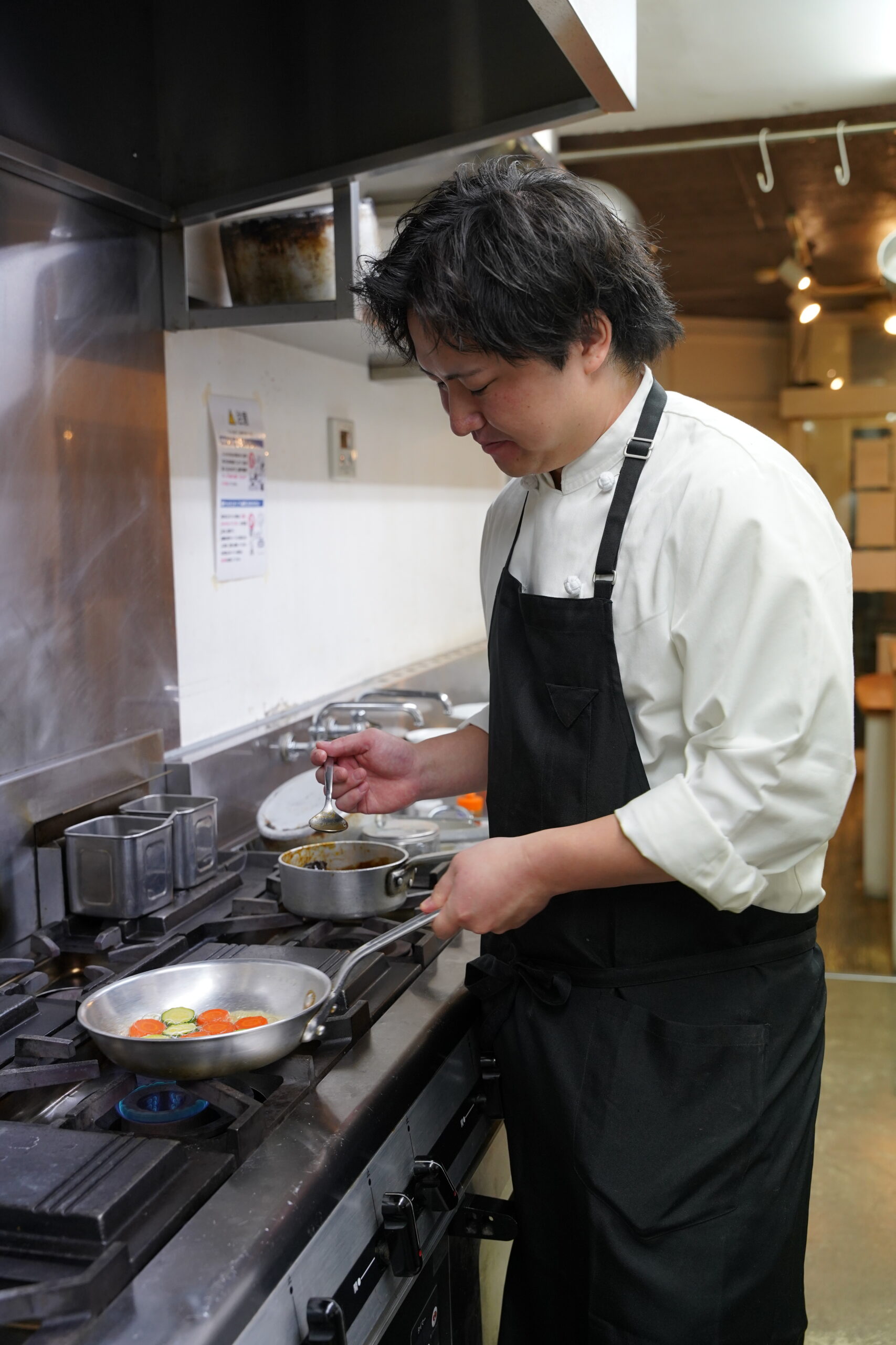 厨房で調理する菊池優也シェフ