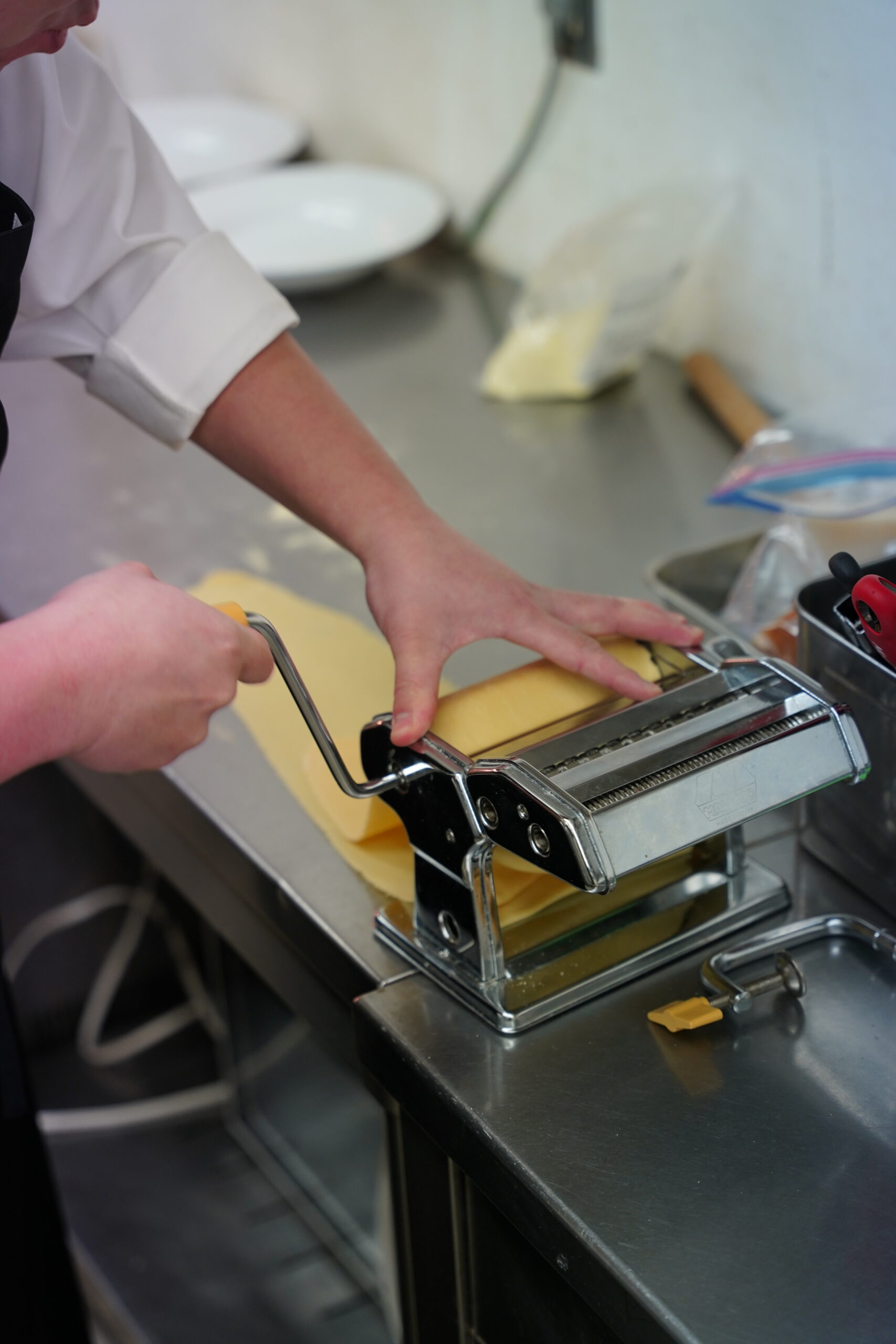 パスタマシンで生地を伸ばす菊池シェフ