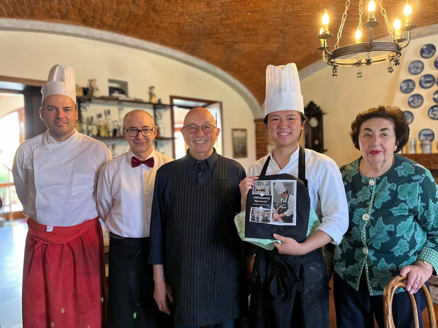 贈られたエプロンを着けた菊池シェフと「マカッレ」のスタッフ